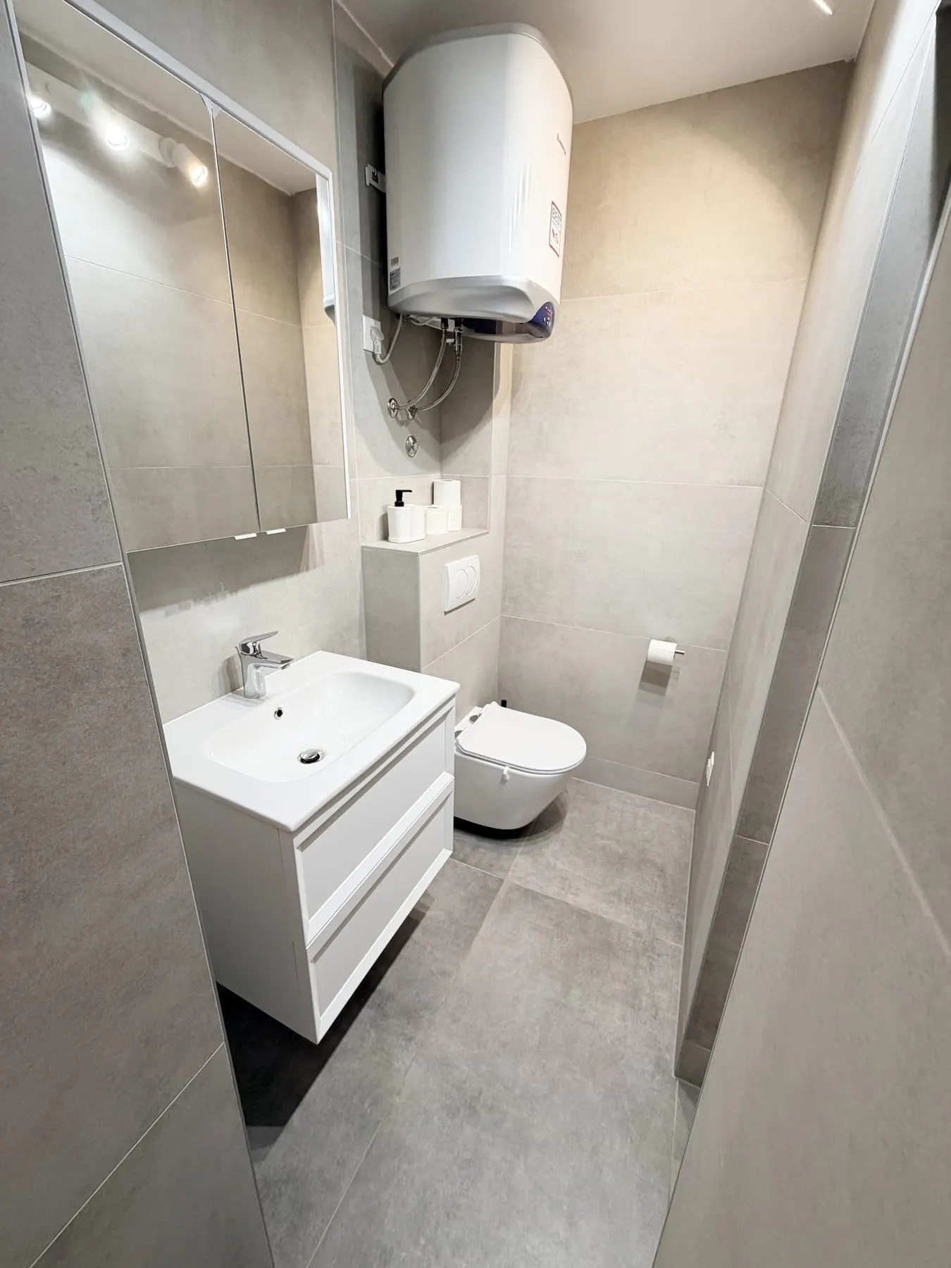 Bathroom with a basin on a white unit, a mirrored cabinet above, and a wall-hung toilet
