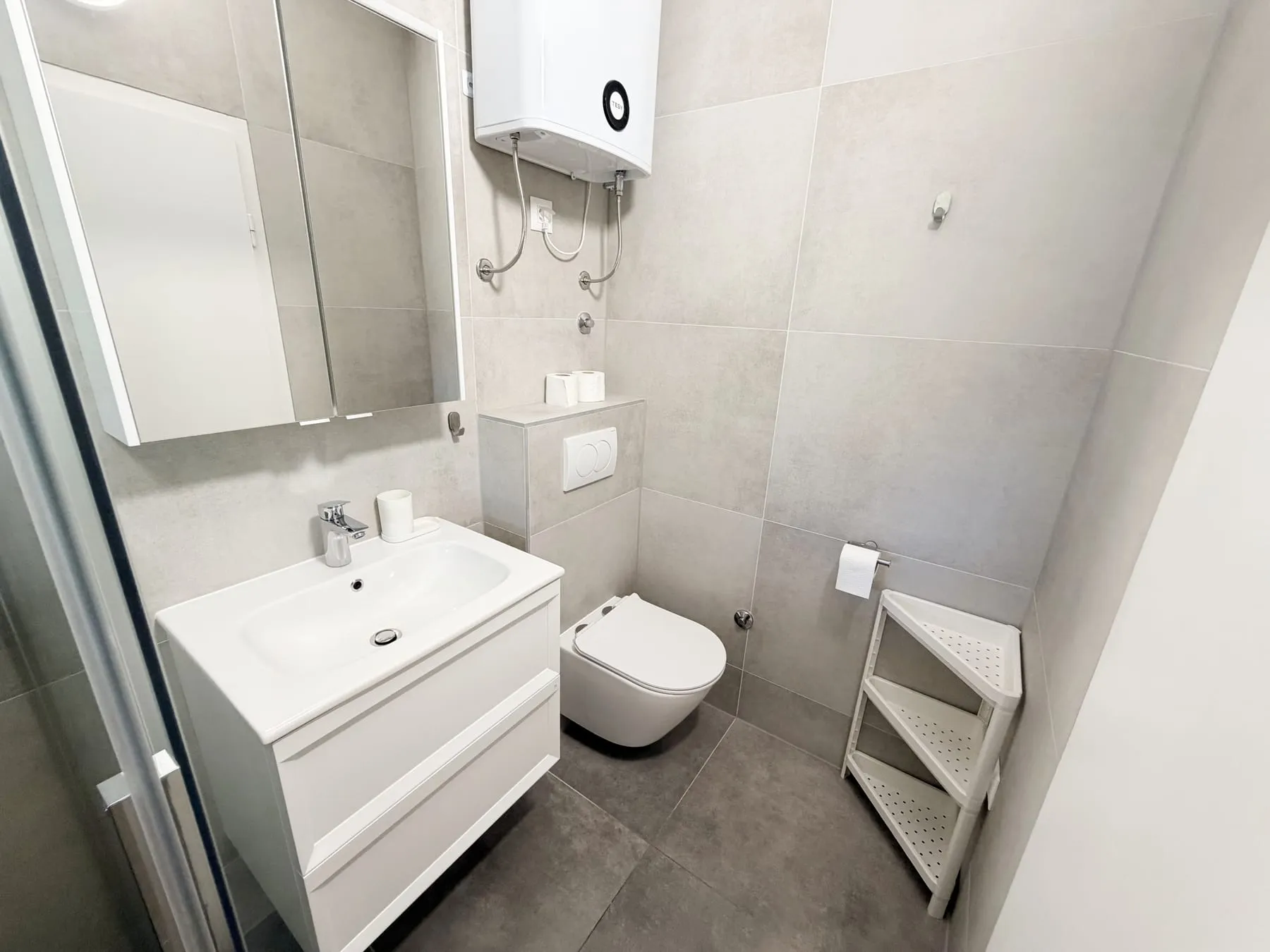 Bathroom with a basin on a white unit, a mirrored cabinet, and a wall-hung toilet