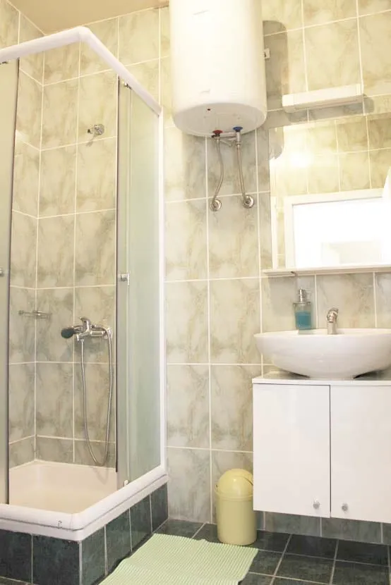 Bathroom with a corner shower cubicle, a basin on a white unit, and a mirror