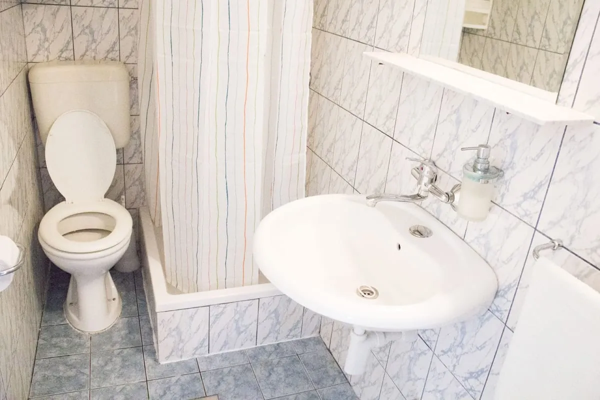 Wall-hung basin and a toilet, with the shower behind a striped curtain