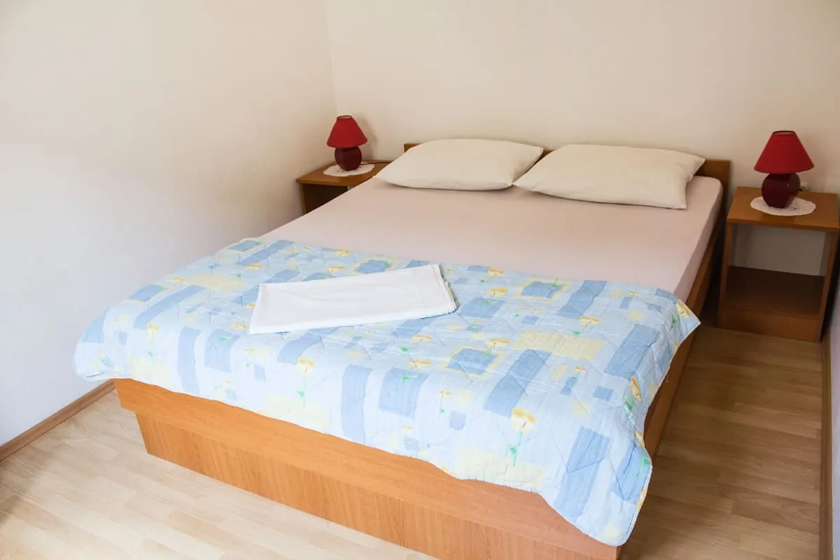 Double bed with two pillows and a red lamp on a bedside table each side