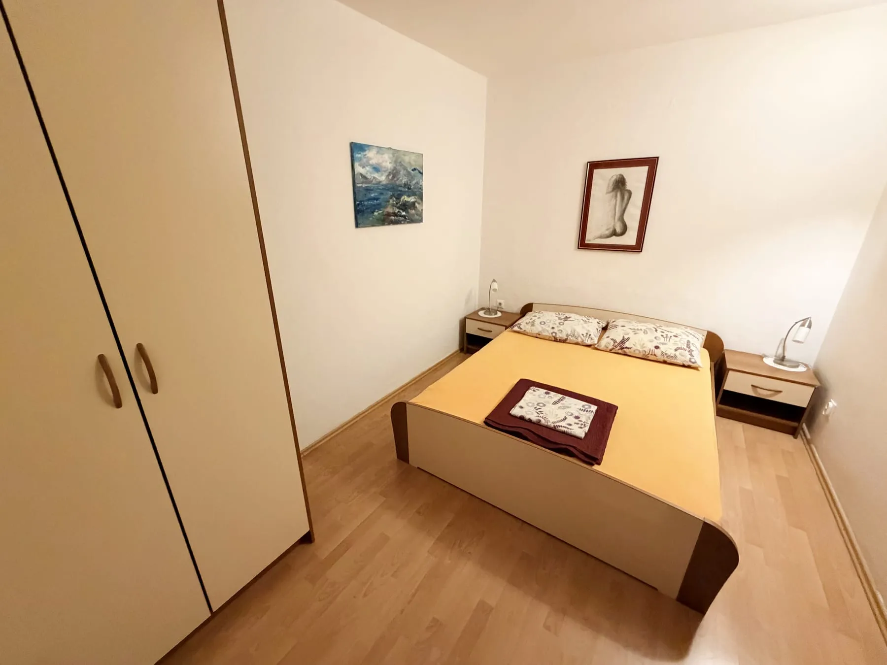 Bedroom with a double bed, a bedside table and lamp on each side, and a tall wardrobe