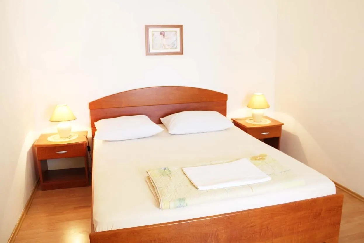 Double bed with a wooden headboard and a lamp on a bedside table each side