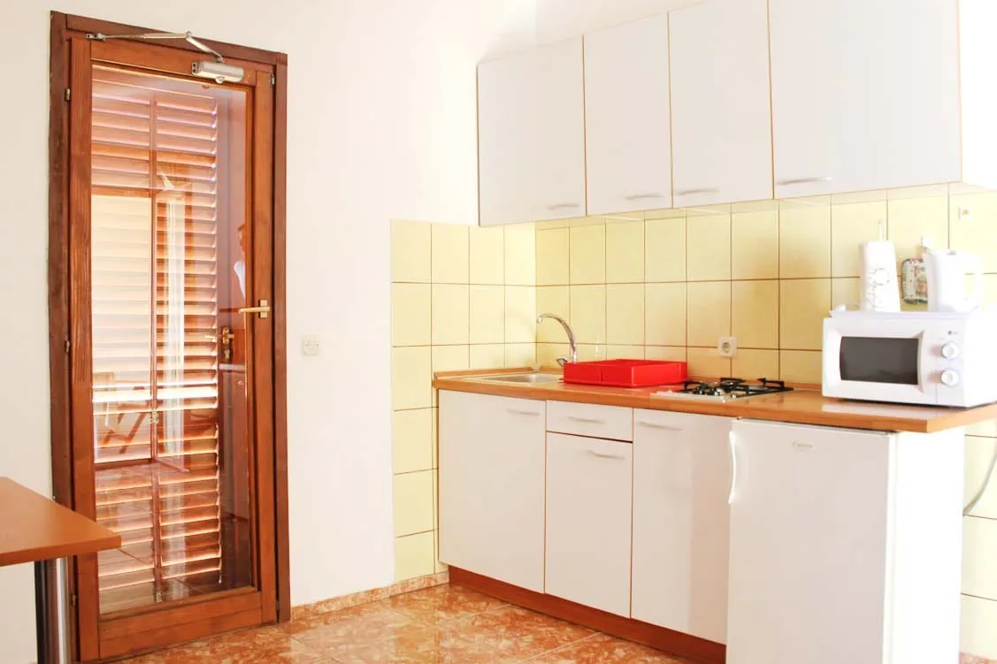 Kitchen with white units, a sink, a gas hob, and a louvred door to the outside