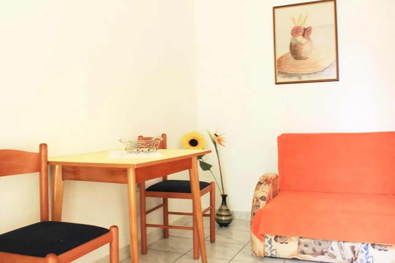 Dining table with two wooden chairs next to an orange sofa bed