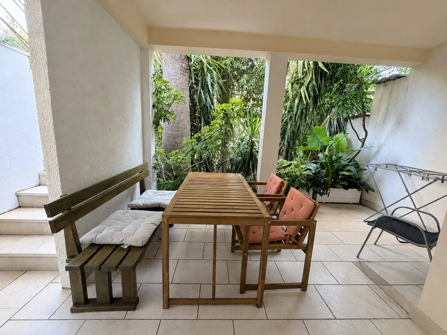 Covered terrace with a wooden table, cushioned chairs and a bench along the wall